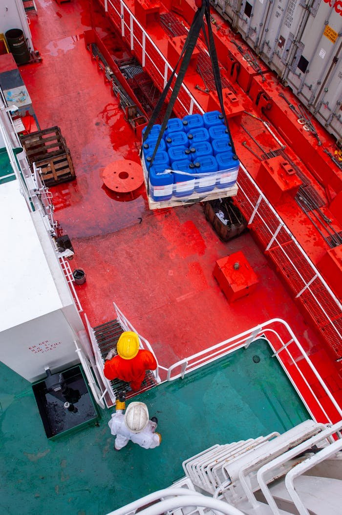 Workers loading supplies onto a ship deck as part of maritime logistics.